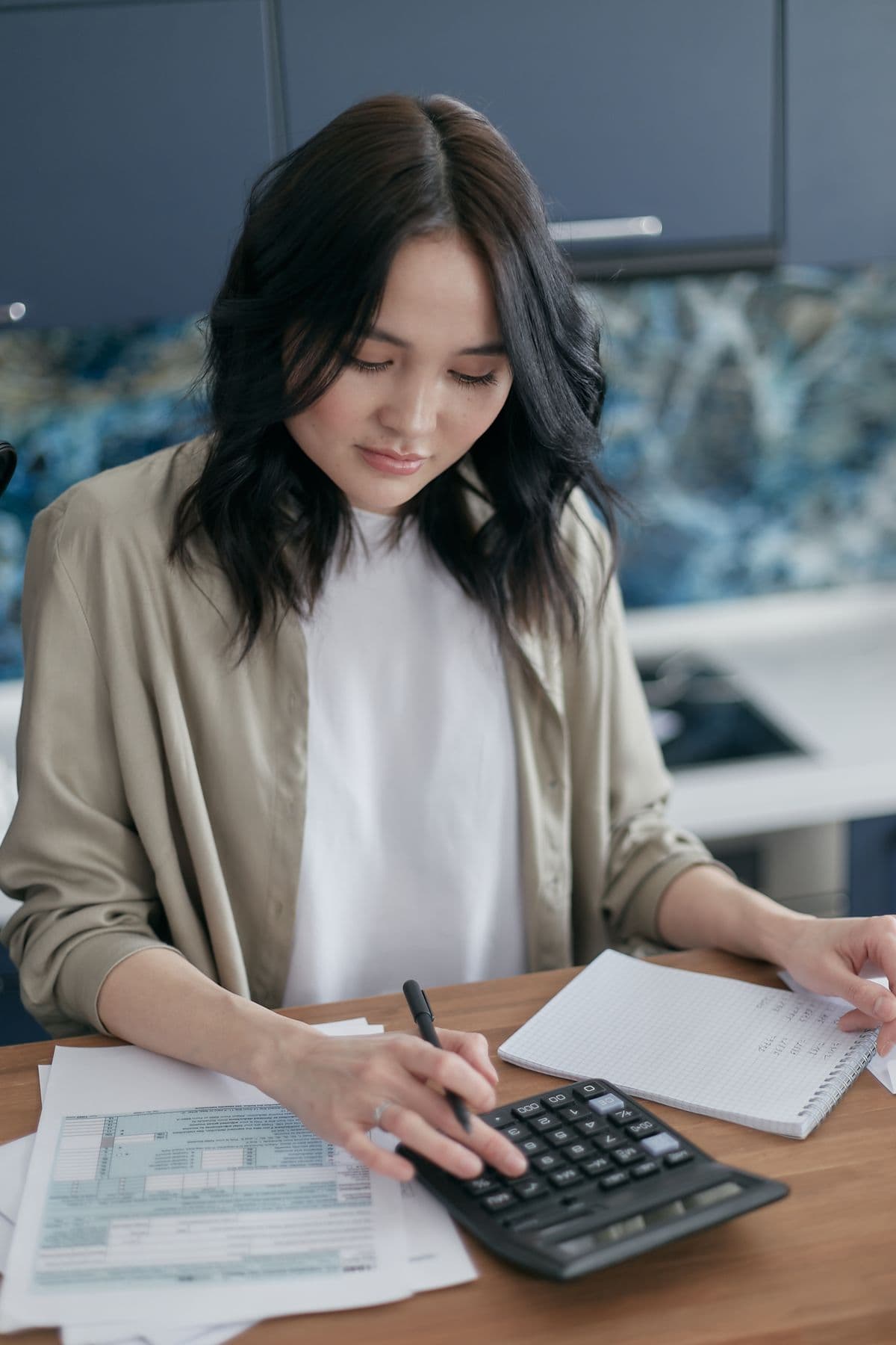 A woman working out her monthly figures with a calculator and a notebook.