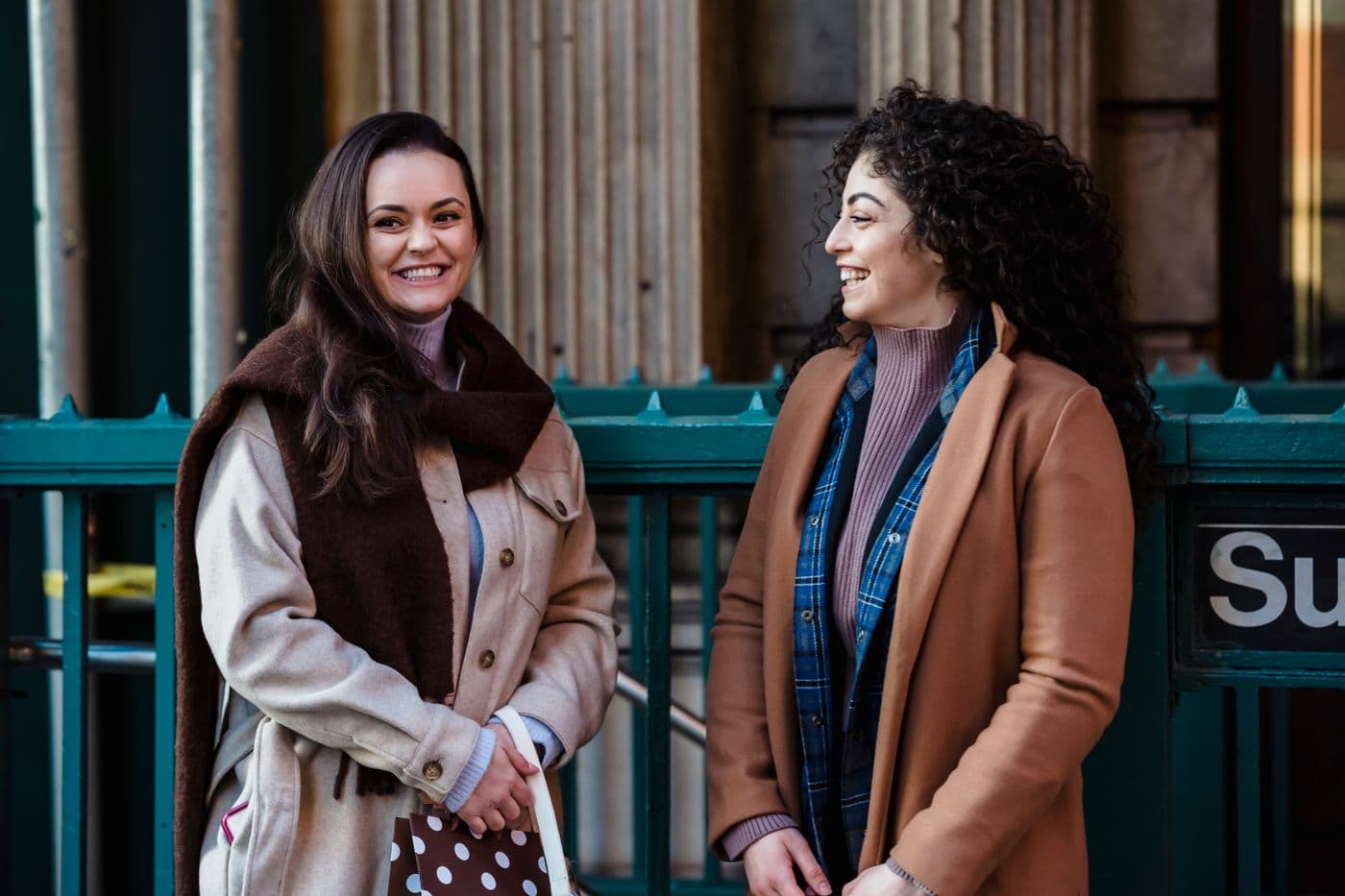 Two women talking and laughing on a city street.