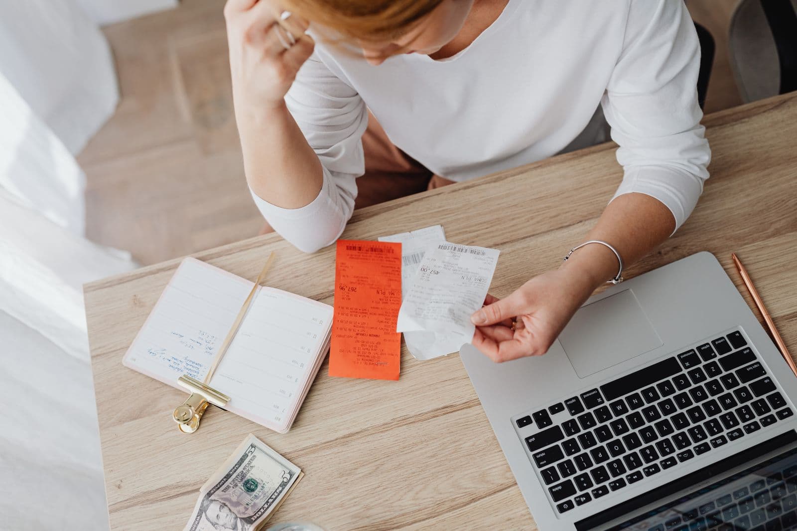 Receipts, a notebook and a laptop spread across a kitchen table.
