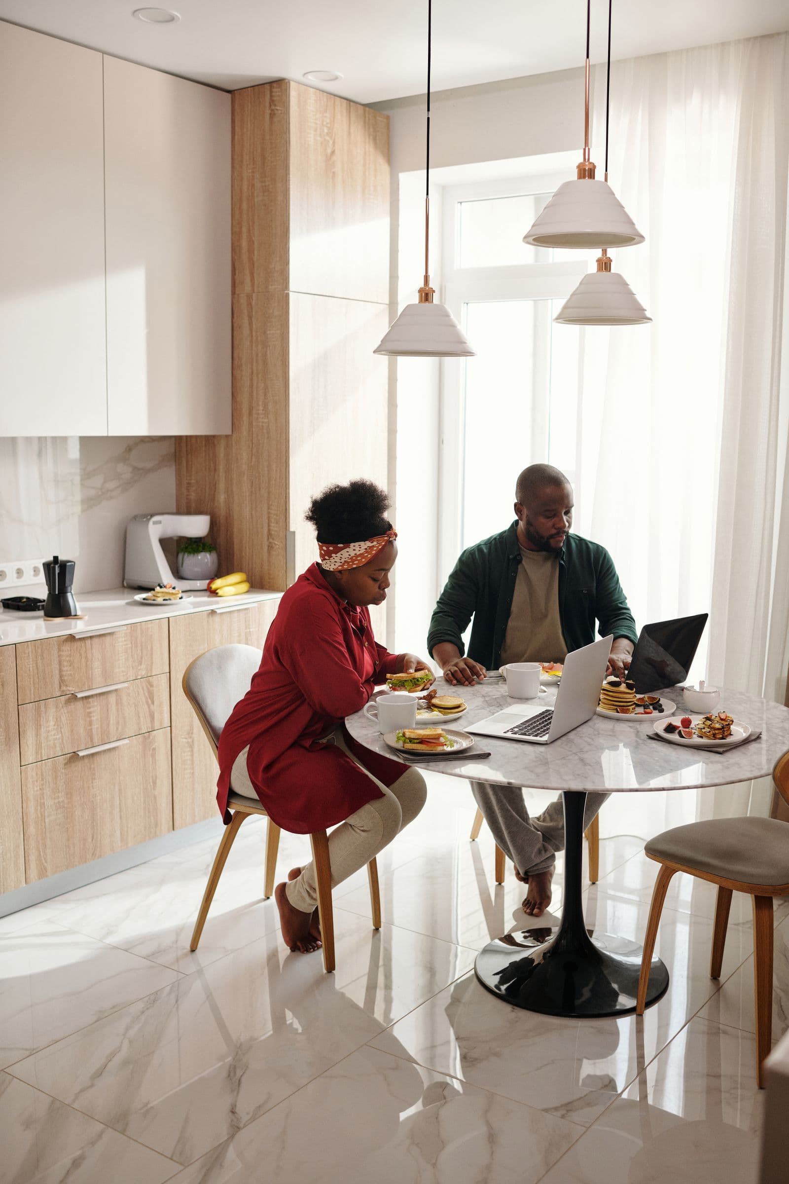 Two people going through paperwork on a laptop at a kitchen table.